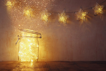 low key and vintage filtered image of fairy lights in mason jar with. selective focus. glitter...