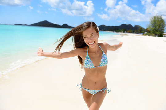 Beach bikini woman happy running with aspiration, joyful, free and playful on Jolly Beach, Antigua Girl on travel vacation holidays having fun. Asian Chinese Caucasian female model.