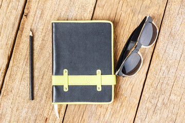 notebook sunglasses on wooden table