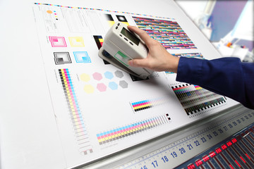 オフセット印刷の色見台で測色する作業員