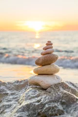 Foto op Plexiglas Stenen piramide op zand symboliseert zen, harmonie, balans. Oceaan © Netfalls