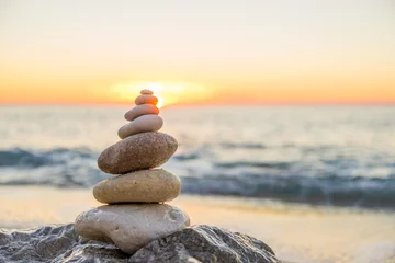 Poster Stenen piramide op zand symboliseert zen, harmonie, balans. Oceaan © Netfalls