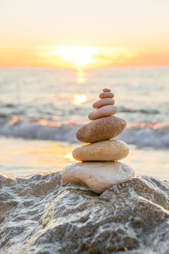Fototapeta Stones pyramid on sand symbolizing zen, harmony, balance. Ocean