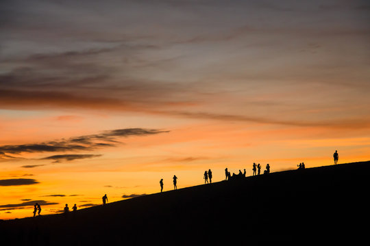 Silhouette people standing on dune in the sunset evening at Red