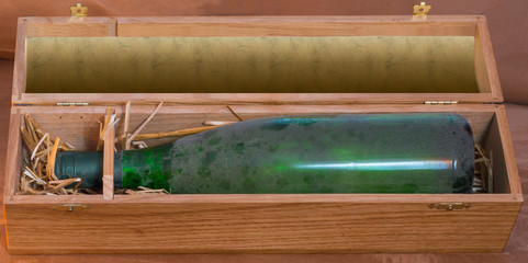 Fototapeta premium Old dusty archived wine bottle in a luxury wooden box or case