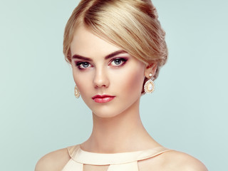 Portrait of beautiful sensual woman with elegant hairstyle.  Perfect makeup. Blonde girl. Fashion photo. Jewelry and dress
