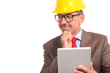 construction engineer with tablet pad looks to side and smiles