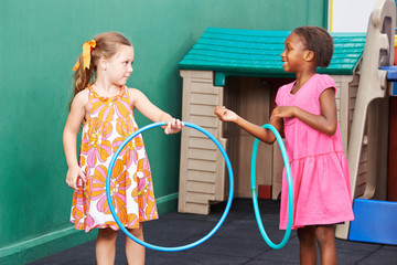 Zwei Kinder spielen mit Hula Hoop Reifen