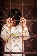 girl standing  behind jail