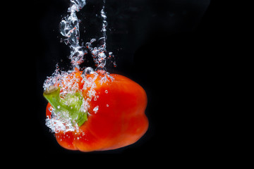 Fresh Red Bell Pepper Splash in Water on Black Background.