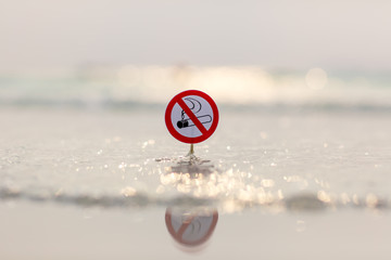 "No smoking" sign on the beach on sea background