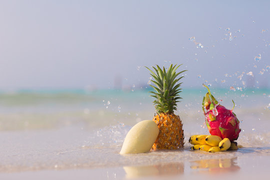 Pineapple, Mango, Dragon Fruit And Bananas  On The Beach On Blue Sea Background