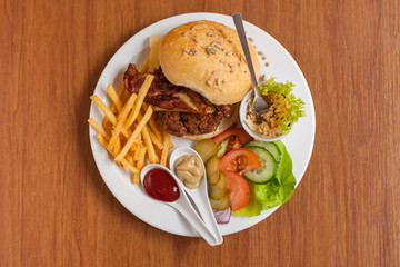 Fresh cheeseburger with chips, dips and vegetables  on the wooden table.