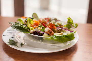 Colorful salad with shrimps on wooden table. Close up.