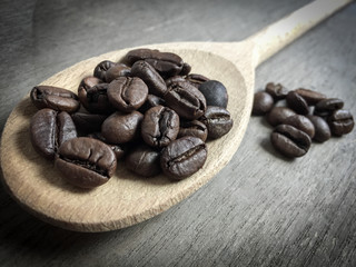 Fine roasted coffee beans on wooden spoon