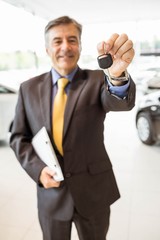 Male driver showing a key after buying a new car