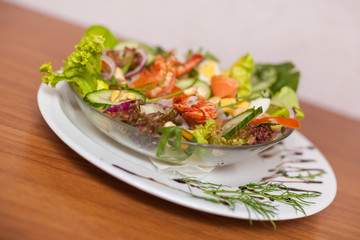 Colorful salad with shrimps on wooden table. Close up.