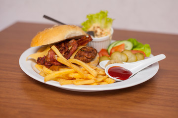 Fresh cheeseburger with chips, dips and vegetables  on the wooden table.