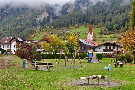 Gemeinde Ried im Oberinntal mit Spielplatz und Kirche im Nebel, Tirol - Österreich