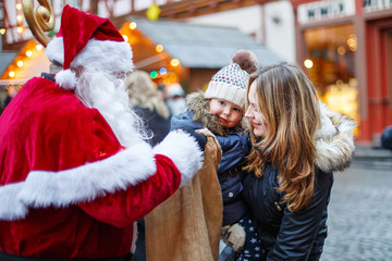 Little toddler girl with mother on Christmas market.