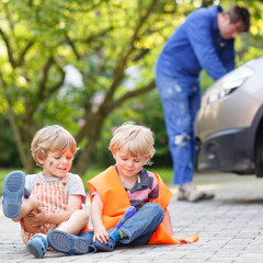 Two little sibling boys in orange safety vest during their fathe