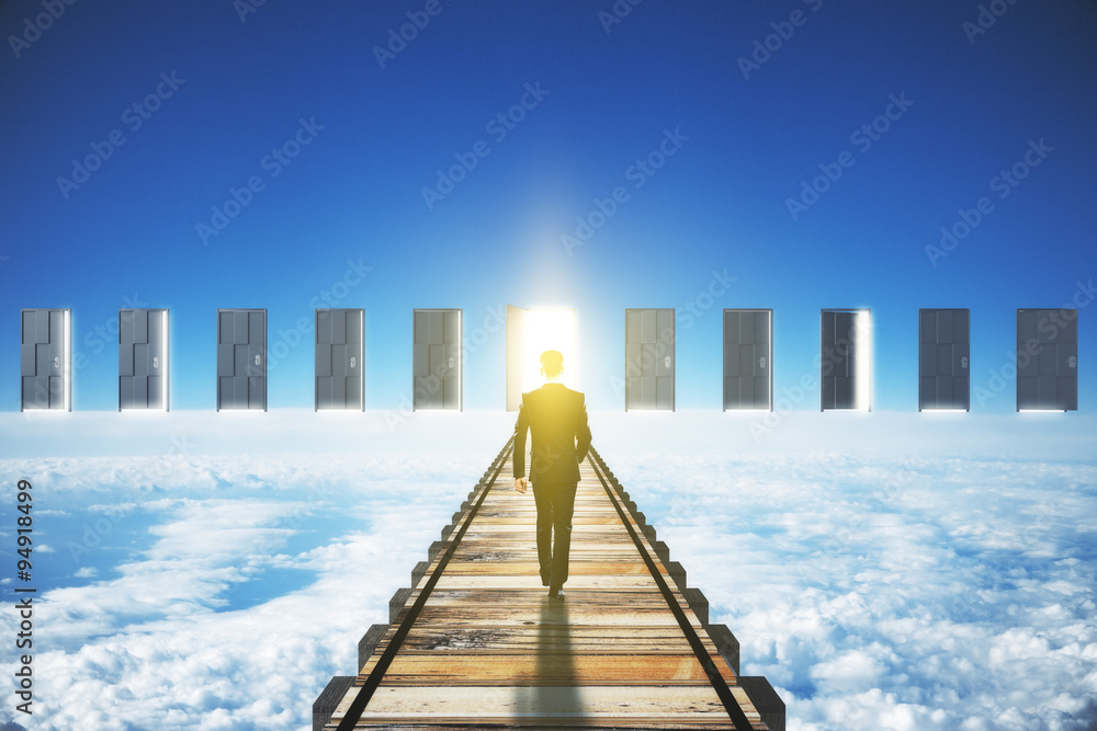 Wall mural man walking to an open door in clouds concept