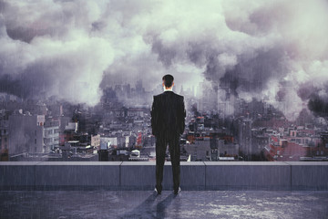 Businessman under the rain and clouds on the top of building