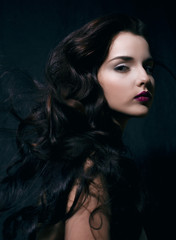 beauty young brunette woman with curly flying hair, femme fatal