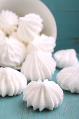 white meringue cake scattered on a blue wooden background. selective Focus