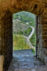 A forged door leading to Angelokastro castle with a34curvy road on background, Corfu, Greece. - 94927261