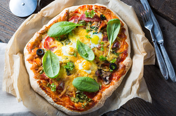 Homemade salami pizza with spinach and quail eggs