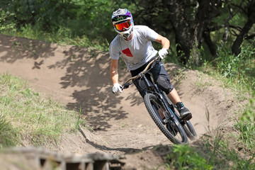 Sportsman in sportswear on a mountain bike rides on the special trail in the extreme style of downhill