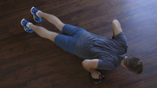 Ariel view of a young man doing press ups in his home using push up bars 
