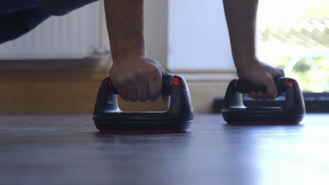 Young man doing press ups in his home using push up bars 