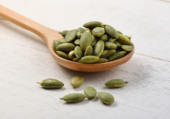 pumpkin seeds in the spoon on white wooden