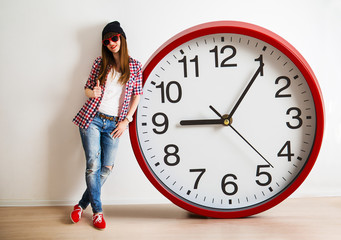 young woman with hat and glasses holding a clock. time managemen