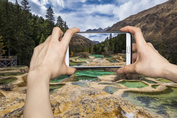 Girl taking pictures on mobile smart phone in Huanglong,China