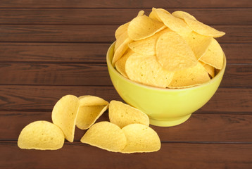 tasty potato chips in green bowl on wooden table
