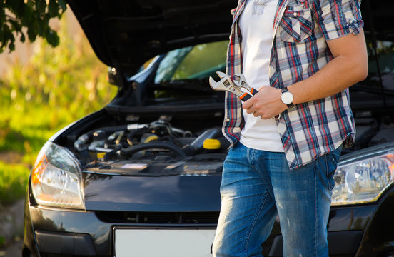 Young Man Looking Under The Hood Of Breakdown Car