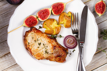 Grilled Pork Chop with Figs on Scewer, Crisp Roasted Potatoes and Thyme. View from above, top studio shot