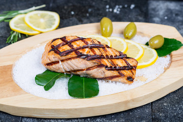 stages of cooking salmon on the grill - cook a delicious salmon fillet grilled served on a wooden plate with olives and lemon sea salt
