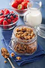 homemade healthy granola in glass jar and berries