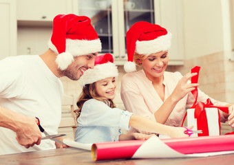 smiling family in santa helper hats with gift box