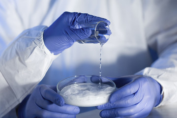 close up of scientists hands with chemicals in lab