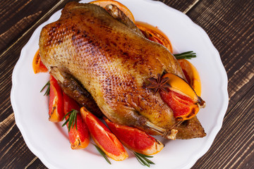 Festive Christmas duck baked with grapefruits and rosemary, glass of wine and candles