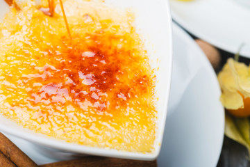 serving traditional сrema Catalana dessert in a bowl on a wooden table in a restaurant close up