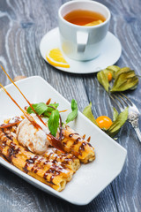 Delicious Dessert Eclair with Caramel and Ice Cream with a cup of tea on a wooden table