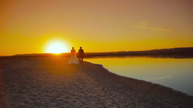 the bride and groom are on the beach at sunset on the sand in the sun