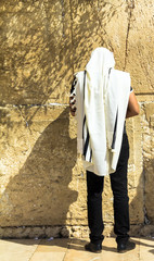 Unidentified jewish worshiper in  tallith and tefillin praying at the Wailing Wall an important jewish religious site