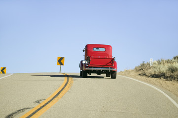 A restored bright Red Roadster hotrod pickup truck, mid-30's, drives rural highway in Kern County near Lockwood Valley, CA